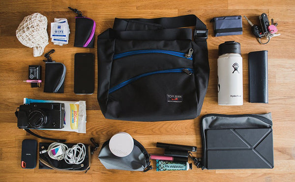 A possible loadout for the Icon -- a few organizer pouches, an eyeglass case, a waterbottle, a wallet, a pair of keys, a camera, and a phone.